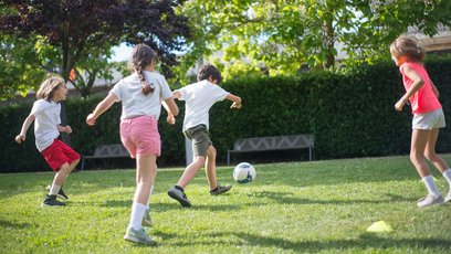 Kinder spielen Fußball im Garten