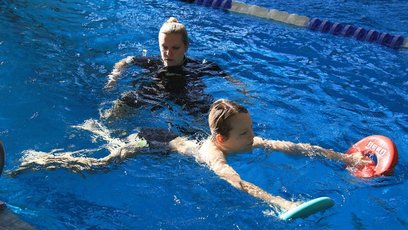 Schwimmtrainerin betreut ein Kind im Wasser