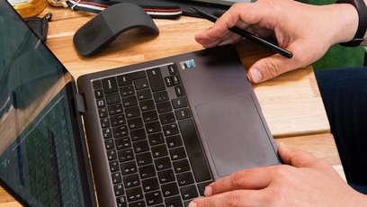 Eine Paar Hände arbeiten an einem Laptop.